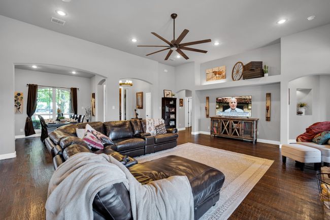 Living room featuring a towering ceiling, dark wood-type flooring, and ceiling fan | Image 7