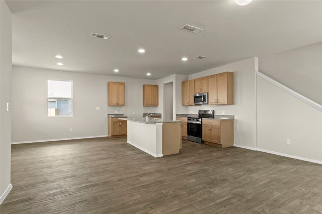 Kitchen featuring appliances with stainless steel finishes, dark wood finished floors, open floor plan, recessed lighting, and an island with sink | Image 22