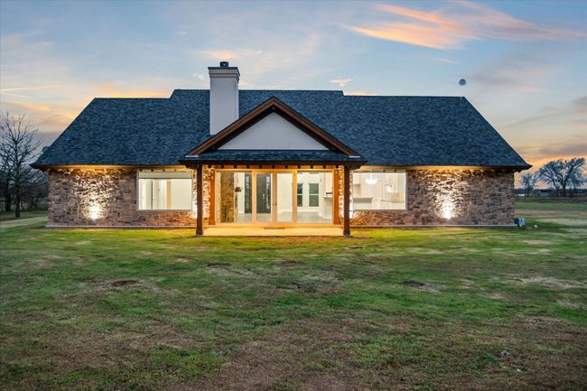 Back house at dusk with a yard, french doors, and a patio | Image 35