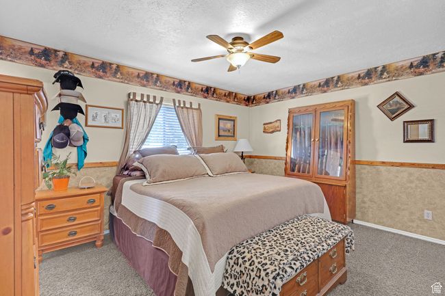 Bedroom featuring a textured ceiling, carpet floors, a wainscoted wall, and a ceiling fan | Image 13