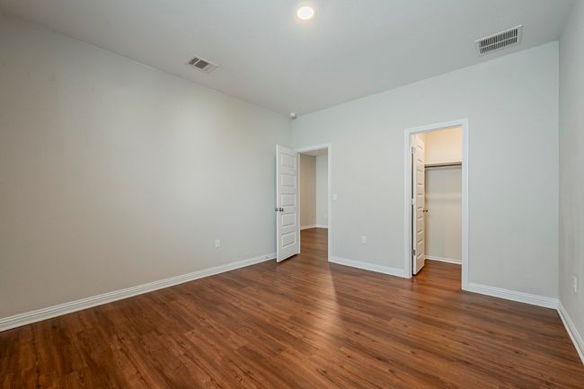 Unfurnished bedroom with baseboards, visible vents, a walk in closet, and dark wood-type flooring | Image 32