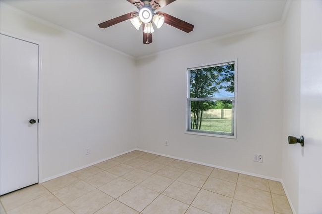 Spare room featuring crown molding, baseboards, a ceiling fan, and light tile patterned floors | Image 17