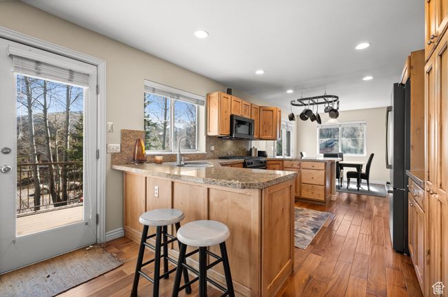 Kitchen with a peninsula, a sink, range with gas cooktop, freestanding refrigerator, and black microwave | Image 9