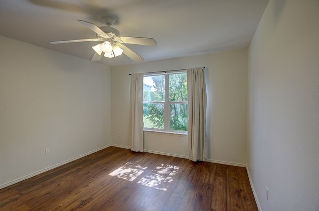 Empty room with wood-type flooring, baseboards, and ceiling fan | Image 7