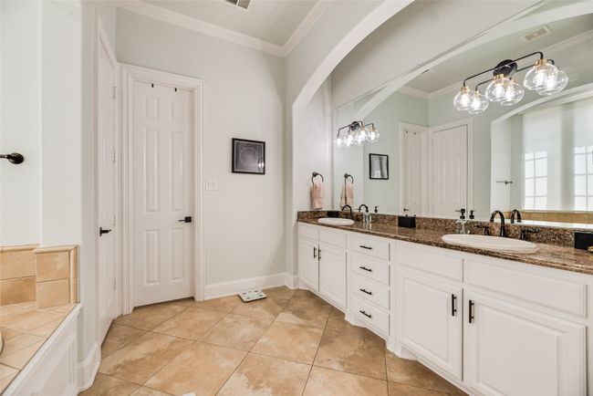 Bathroom with double vanity, crown molding, tile patterned flooring, a chandelier, and a bathtub | Image 10