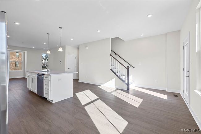 Kitchen with dark wood-style flooring, baseboards, an island with sink, white cabinets, and dishwasher | Image 6