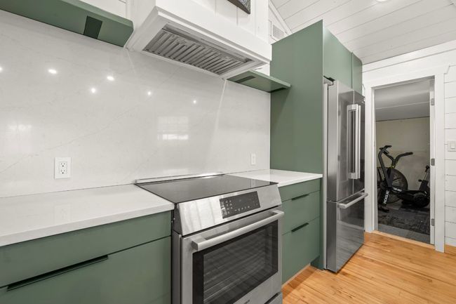 Kitchen featuring premium range hood, stainless steel appliances, light countertops, and green cabinetry | Image 11