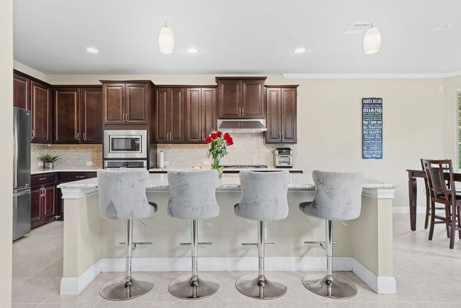 Kitchen with stainless steel appliances, hanging light fixtures, under cabinet range hood, baseboards, and recessed lighting | Image 9
