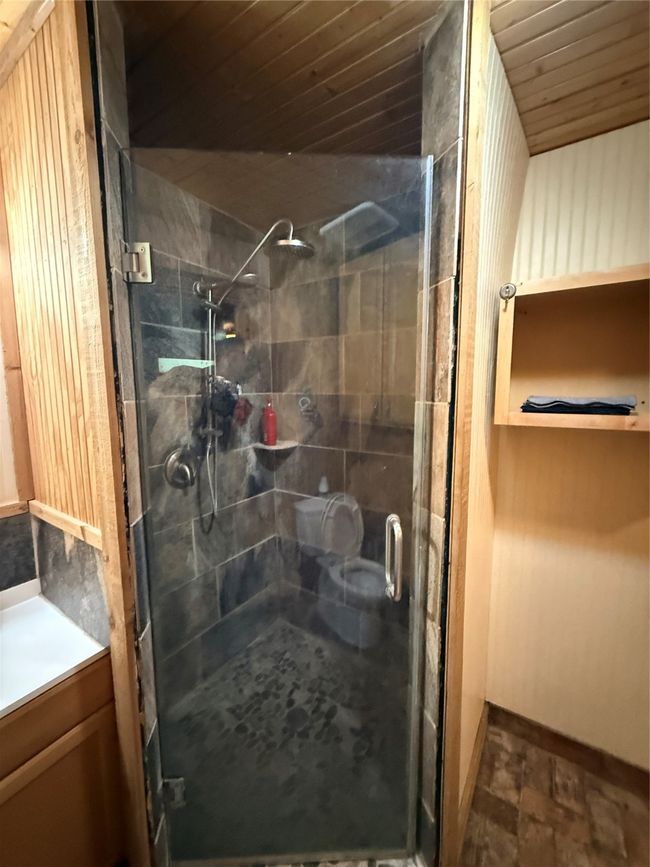 Full bathroom featuring a shower stall, baseboards, vanity, wooden ceiling, and stone finish flooring | Image 12