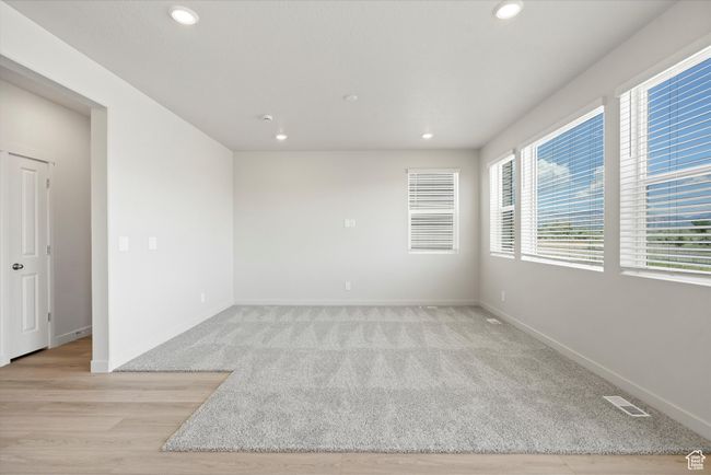 Empty room with recessed lighting, light colored carpet, and light wood-type flooring | Image 12