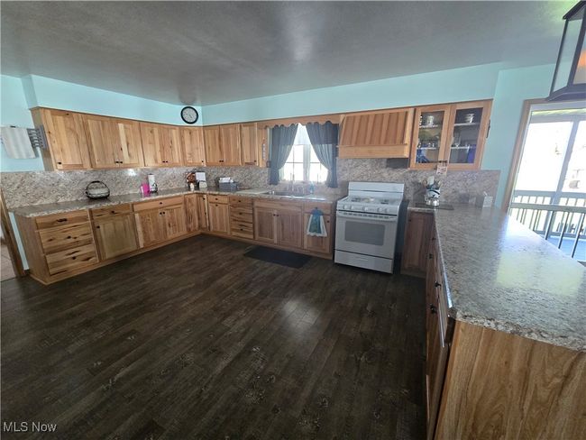 Kitchen with a sink, dark wood-type flooring, gas range gas stove, a peninsula, and tasteful backsplash | Image 30