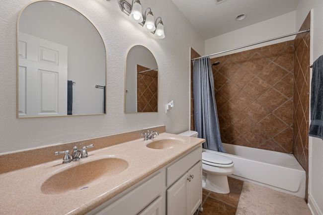 Bathroom with toilet, shower / bath combination with curtain, a sink, and double vanity | Image 28