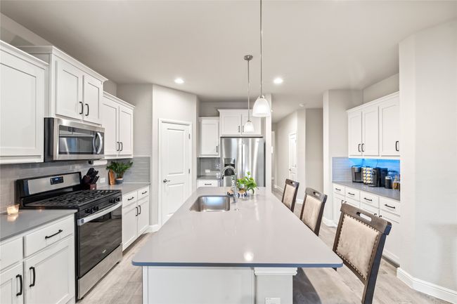 Kitchen featuring an island with sink, a sink, white cabinetry, appliances with stainless steel finishes, and light wood finished floors | Image 7