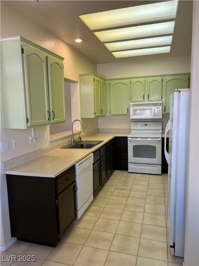 Kitchen featuring white appliances, green cabinetry, a sink, light countertops, and recessed lighting | Image 11