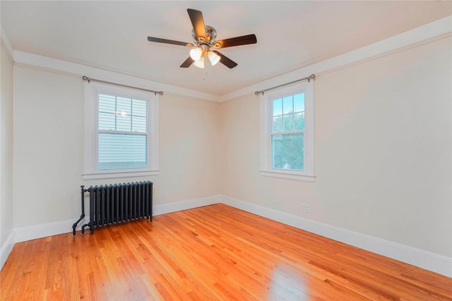 Empty room with radiator heating unit, light wood-type flooring, baseboards, and ceiling fan | Image 19