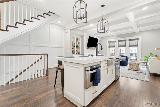 Kitchen with a notable chandelier, open floor plan, stainless steel oven, coffered ceiling, and dark wood-style flooring | Image 16