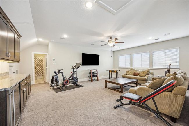 This spacious, carpeted flex room on the third floor is perfect for entertaining. It includes a kitchenette with cabinetry, and a mini-fridge. Additionally, there's a bedroom and a full bathroom. | Image 23