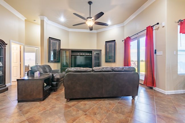Living room featuring crown molding, a ceiling fan, and tile patterned floors | Image 10