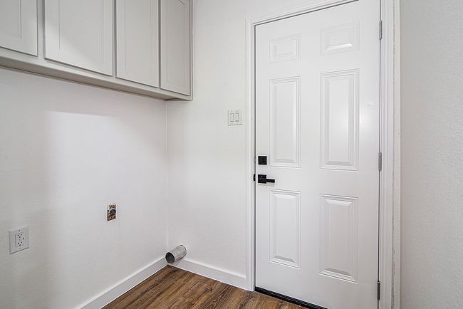 Laundry area featuring hookup for an electric dryer, cabinet space, baseboards, and dark wood-style flooring | Image 17