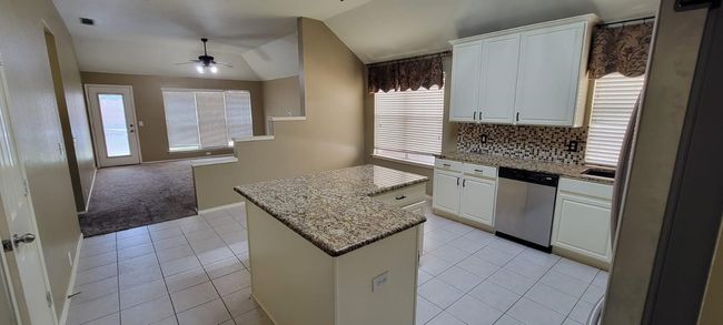 Kitchen featuring a kitchen island, backsplash, lofted ceiling, a ceiling fan, and stainless steel appliances | Image 7