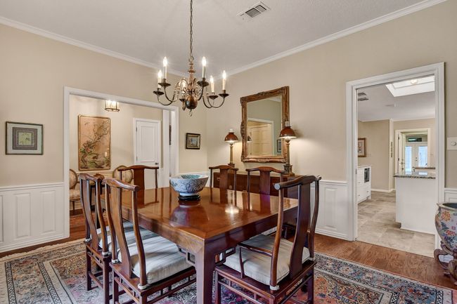 Dining room featuring ornamental molding, wainscoting, a chandelier, light wood-style floors, and a decorative wall | Image 8