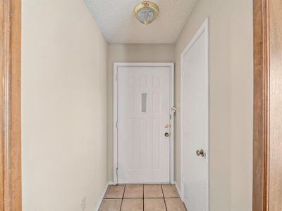 Doorway featuring a textured ceiling and light tile patterned floors | Image 3