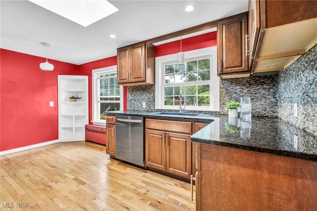 Kitchen featuring appliances with stainless steel finishes, a skylight, radiator heating unit, light wood flooring, and maple cabinetry | Image 10