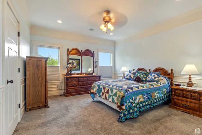 Bedroom featuring carpet floors, a decorative wall, ornamental molding, wainscoting, and a ceiling fan | Image 18