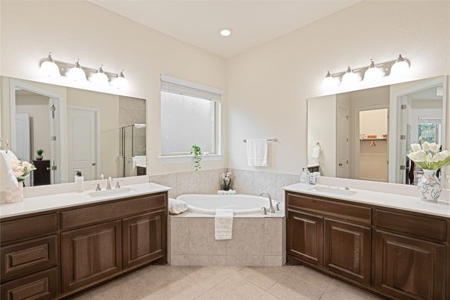 Full bathroom with a stall shower, tile patterned flooring, two vanities, and a bath | Image 21