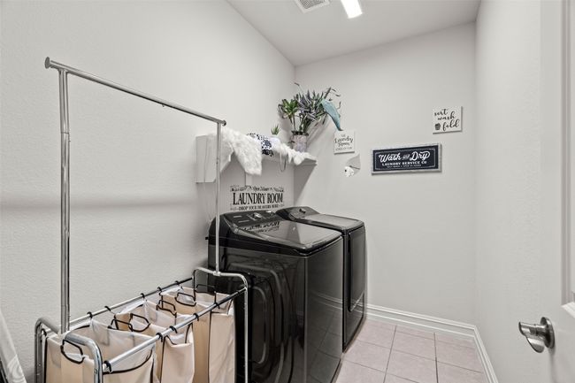 Laundry area featuring baseboards, tile patterned floors, visible vents, washer and clothes dryer, and laundry area | Image 9