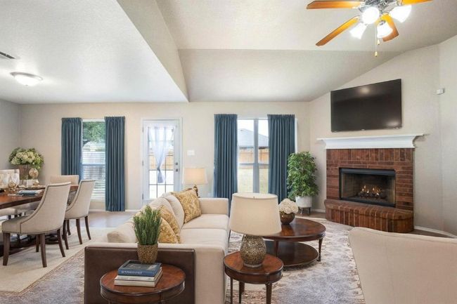Living room with vaulted ceiling, plenty of natural light, a ceiling fan, a fireplace, and carpet flooring | Image 6