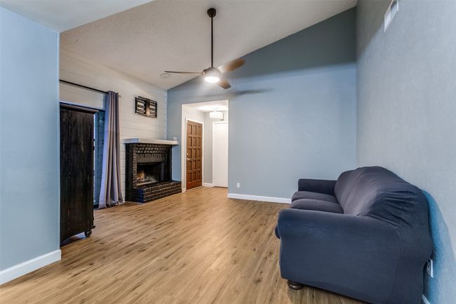 Living room with lofted ceiling, wood finished floors, a fireplace, and ceiling fan | Image 5