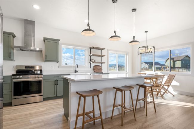 Kitchen featuring stainless steel electric range oven, wall chimney exhaust hood, green cabinetry, light wood-style floors, and recessed lighting | Image 14