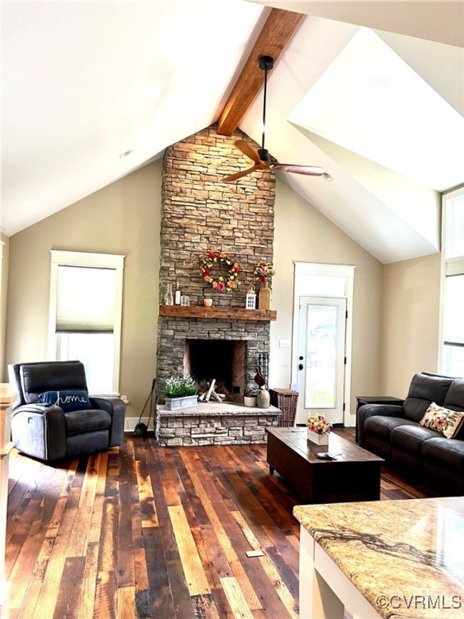 Living room with reclaimed oak wood finished floors, ceiling fan, and a stone fireplace | Image 7
