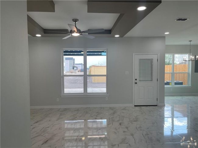 Empty room with baseboards, recessed lighting, a ceiling fan, a chandelier, and marble finish flooring | Image 4