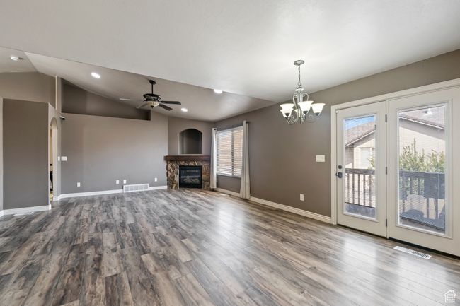 Unfurnished living room with visible vents, a healthy amount of sunlight, and a stone fireplace | Image 4