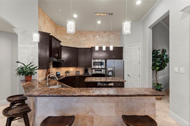 A sleek breakfast bar anchors the kitchen, blending seamlessly with the open layout and offering additional seating and serving space with effortless style. | Image 19