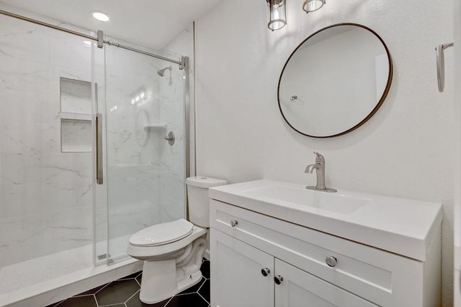 Bathroom featuring toilet, a marble finish shower, vanity, and tile patterned floors | Image 19