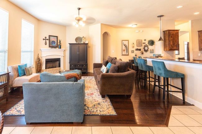 Living area with arched walkways, hardwood / wood-style floors, ceiling fan, a fireplace, and recessed lighting | Image 9