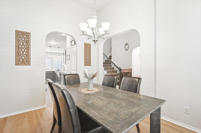 Dining room with arched walkways, light wood-style flooring, a chandelier, and stairway | Image 7