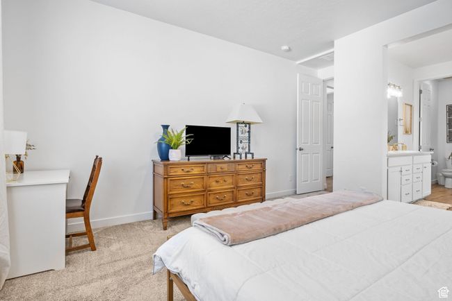 Bedroom featuring light colored carpet, a sink, baseboards, and ensuite bathroom | Image 18
