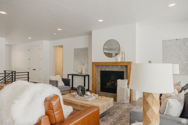 Living area with recessed lighting, a tile fireplace, and wood finished floors | Image 11