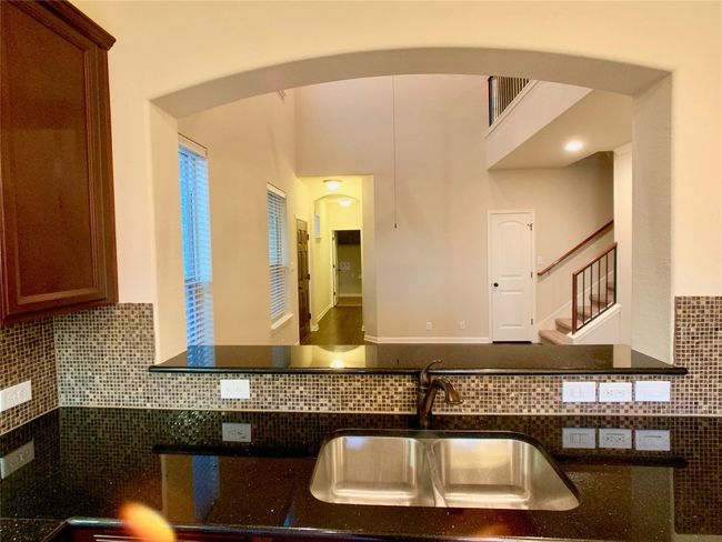 Kitchen with a sink, arched walkways, decorative backsplash, and dark stone countertops | Image 16