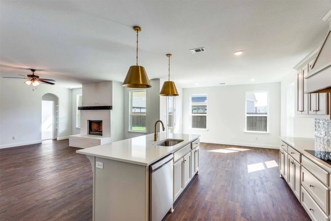 Kitchen featuring sink, hanging light fixtures, stainless steel dishwasher, dark hardwood / wood-style floors, and a kitchen island with sink | Image 9