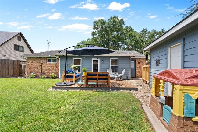 This backyard features a cozy wooden deck, providing a welcoming atmosphere for relaxation and play. | Image 24