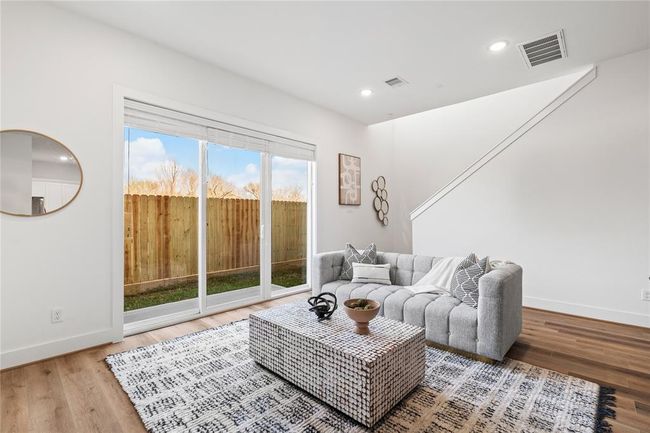 Featuring high ceilings, recessed lighting, and crisp white walls, this living area offers a bright and airy atmosphere. | Image 10