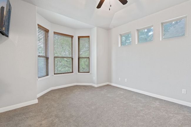 Empty room with bay window, ceiling fan, carpet floors, and baseboards | Image 27