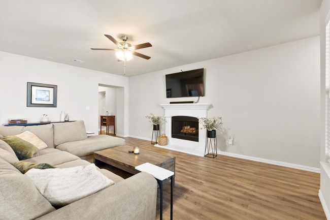 Living room featuring ceiling fan, wood finished floors, and a fireplace with flush hearth | Image 6