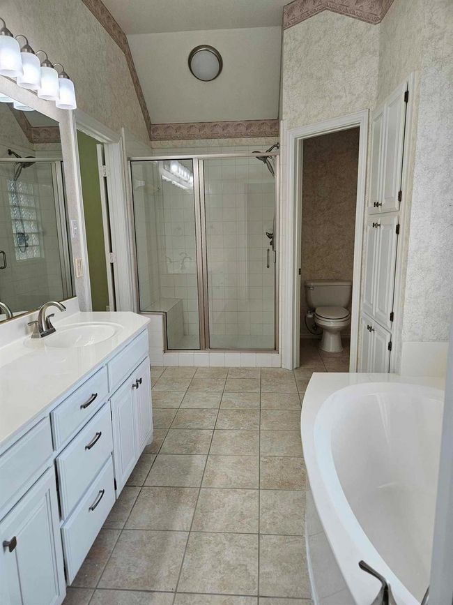 Full bath featuring a shower stall, vanity, a bath, tile patterned floors, and lofted ceiling | Image 16