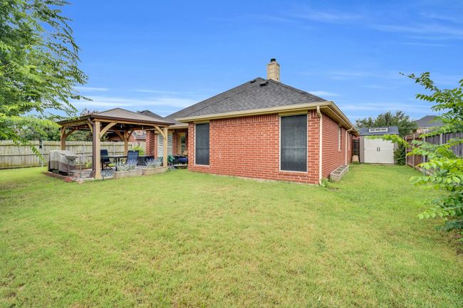 Back of property featuring a gazebo, a storage unit, a chimney, and a fenced backyard | Image 37